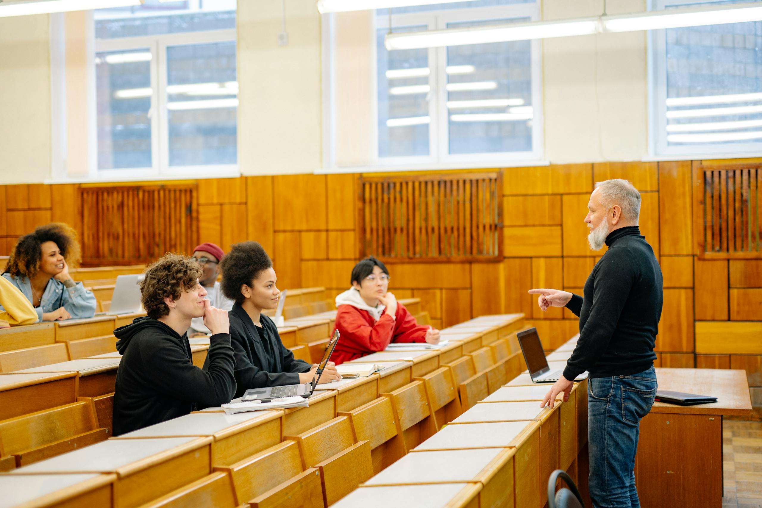 A diverse group of university students engaging with a professor during a classroom lecture.