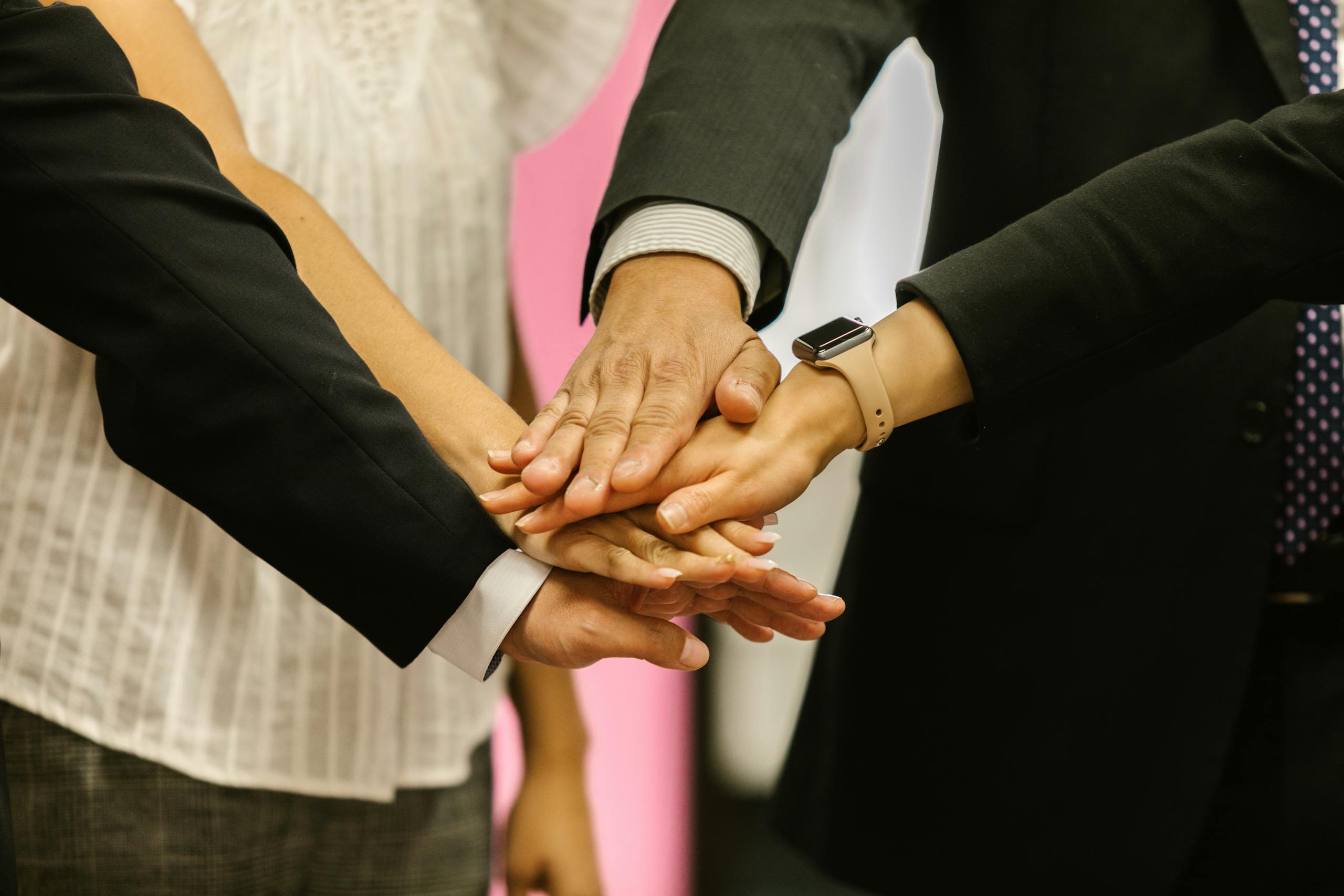 Close-up of colleagues huddling hands symbolizing teamwork and unity.